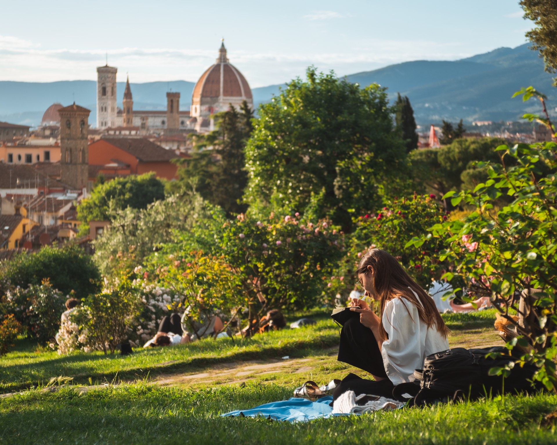 Joven leyendo sobre el césped con vistas a Florencia